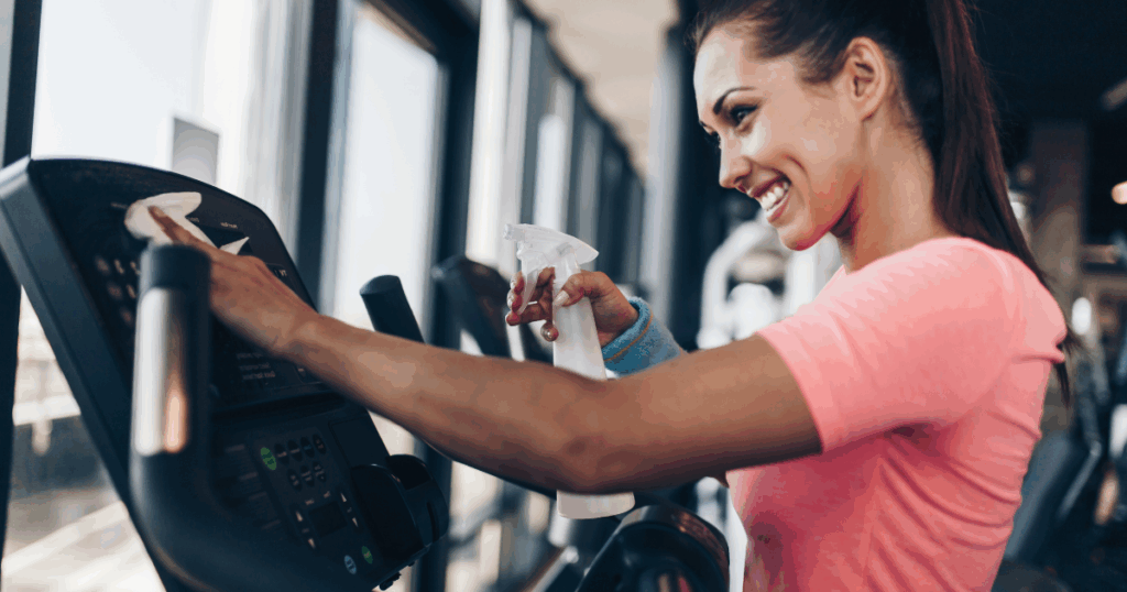 How to Maintain Your Gym80 Fitness Machines for Long-Lasting Use 1 Smiling woman cleaning gym equipment to maintain a safe and healthy fitness environment